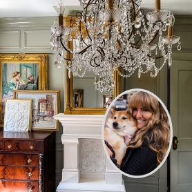 Ashley Piomelli and her puppy's image is inset over a French-inspired room with large crystal chandelier, faux fireplace with large gilt mirror, and a vignette of works of art layered atop a mahogany chest of drawers. | BRG