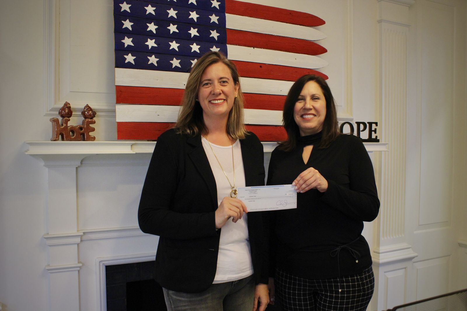 Christie Spooner (left), managing partner of BRG presents Carla Miklos (right), executive director of Operation Hope of Fairfield with a check for over $5,000 which includes the $4,300 colllected on the sale of the vase.
