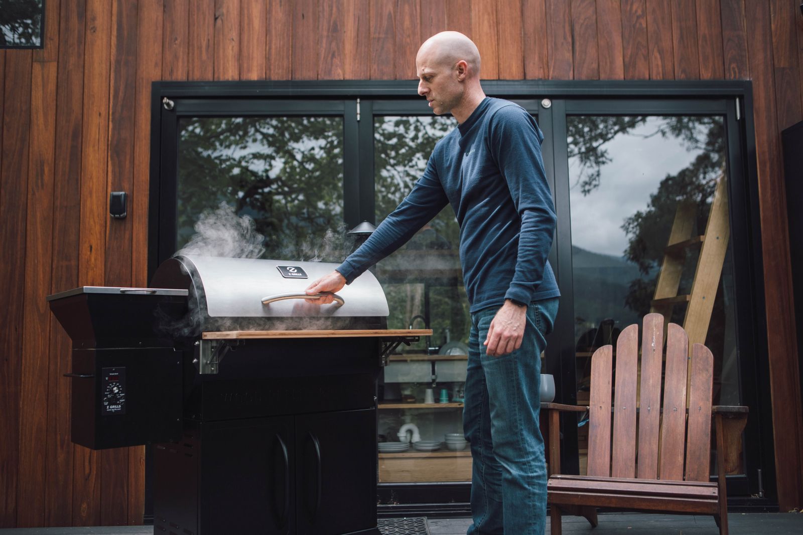 A man next to a barbecue with smoke coming out.